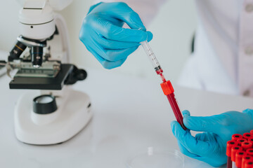 A doctor takes a blood sample tube from a shelf with an analyzer in the lab. Technician holding...