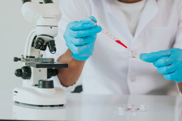 A doctor takes a blood sample tube from a shelf with an analyzer in the lab. Technician holding blood test tube in research lab.