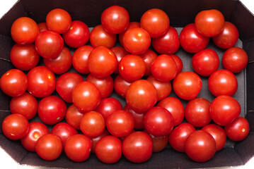 Top view of ripe cherry tomatoes in a cardboard box. © svdolgov