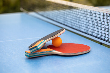 Table tennis. Blue ping pong table. Ping pong rackets and ball. The concept of sport and healthy...