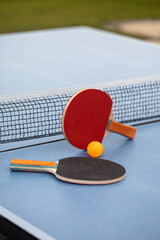 Table tennis. Blue ping pong table. Ping pong rackets and ball. The concept of sport and healthy lifestyle. - obrazy, fototapety, plakaty