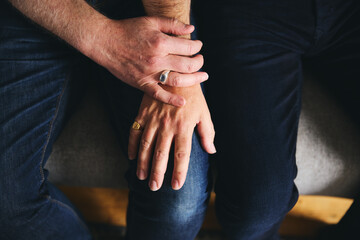 Close in shot of older male same sex couple holding hands