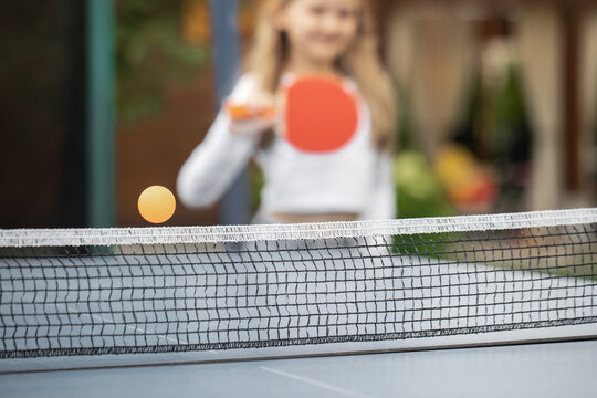 The girl plays table tennis. A girl hits a table tennis ball with a racket. Submission of the ball. Sport games. Sport lifestyle concept.
