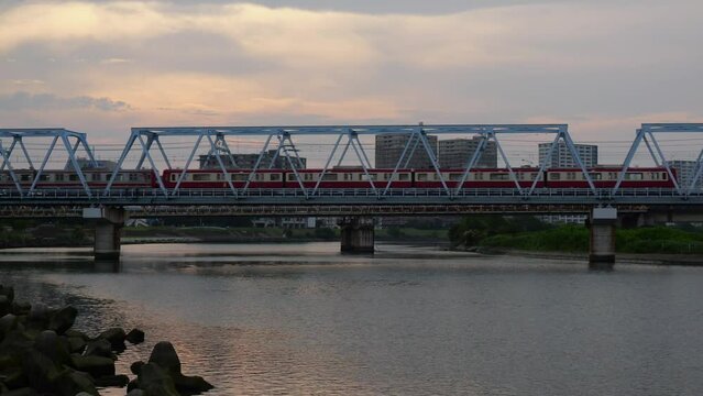 電車が鉄橋を渡る川の夕景。