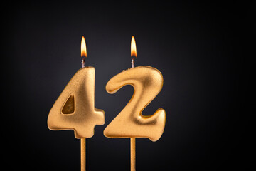 Golden candle 42 with flame - Birthday card on dark luxury background