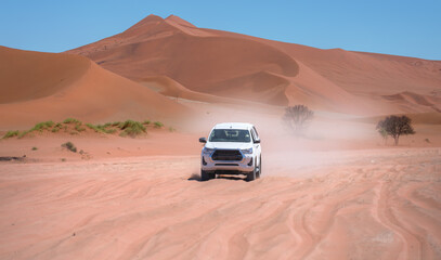 4X4 Suv vehicle rides through the sand dune Namib desert - Namibia - obrazy, fototapety, plakaty
