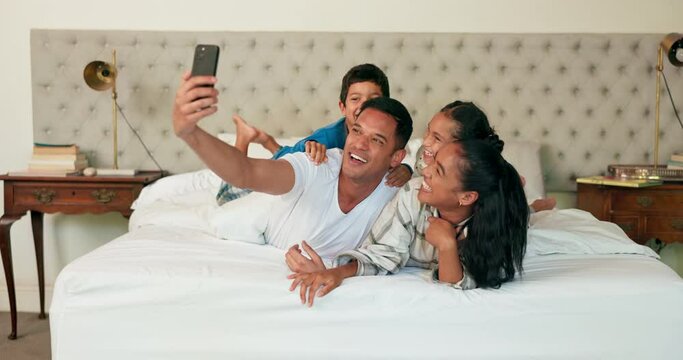 Phone, selfie and family together on bed for happy portrait, memory and social media post of bonding, quality time or weekend. Morning with dad, mom and children in bedroom waking up and relaxing
