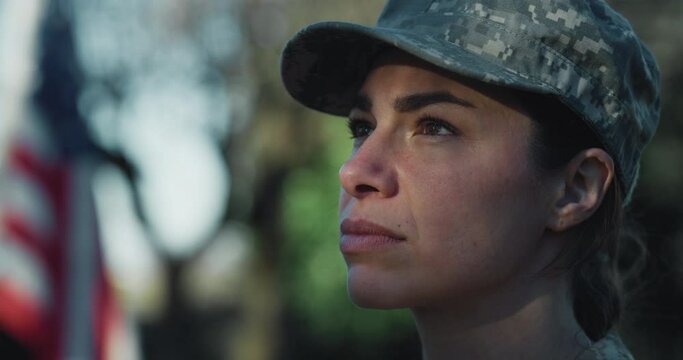 Close Up Portrait of Female Patriotic Soldier Looking Up with the American Flag in the Background. Dedicated Woman in Camouflage Military Uniform Reporting for Duty, Showing Loyalty to Her Country
