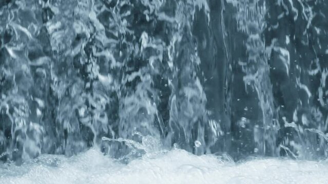Beautiful natural waterfall background with falling crystalline water flow and splashing drops with foam. Scene with blue and cyan color, perspective, close up, super slow motion, hd. ProRes 422 HQ.