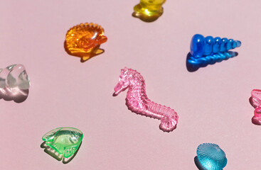 Marine transparent colorful figurines or kid's toys on the pink background. Summer sea vacation concept composition. 