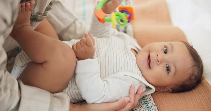 Baby child, parent and rattle on bed with mama, playing or care in family home, learning or childhood development. Portrait, infant kid and mother for games, bonding and happy with toys in nursery