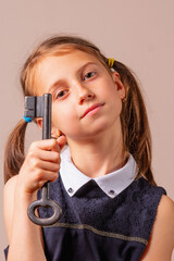 Psychological portrait of beautiful young girl holding big key as symbo of searching for answers. Vertical image.