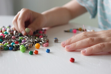 Process of making a bracelet from a thread and colored beads, concept of hobby
