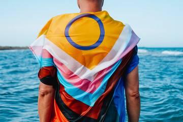 person in the sea wrapped in a progress pride flag