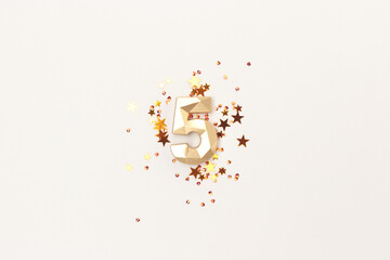 Golden number five and stars confetti on a gray background. Festive shiny concept.