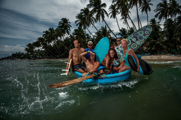 Group of surfers ride on vietnam wooden boat to surf session on coastal vilage