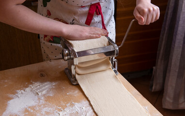 Automation of the process of working with the test at home. The girl rolls out the dough using a pasta dough rolling machine. cooking sfogliatelle is a pleasure. technologists in the kitchen