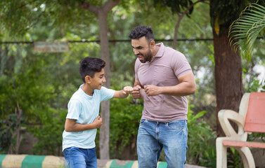 joyful Indian father with son dancing together at park during walk - concept of Happy moments, playful bonding and Family fun.