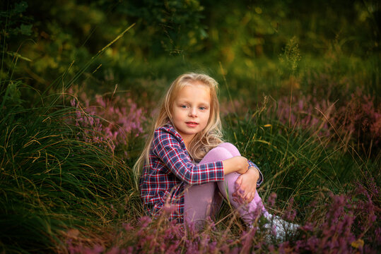 Little blonde girl sitting in heather