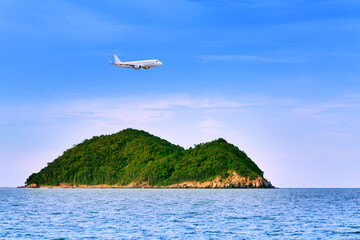 Naklejka premium Commercial airplane above sea with island in summer season and clear blue sky over beautiful scenery ocean background, Concept business travel and transportation summer vacation travel.