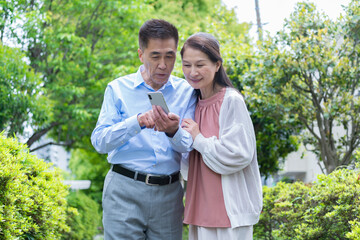 携帯を見る夫婦