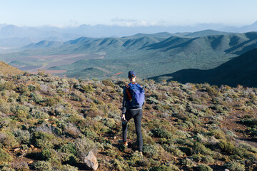 A man hiking in the mountains looking over a vast unexplored wilderness during an adventure hike.