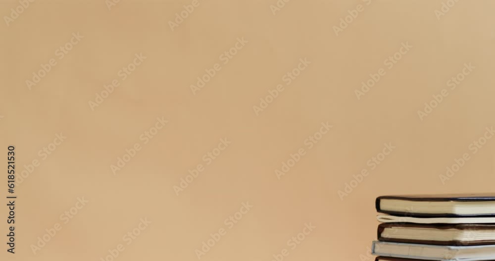 Canvas Prints Close up of stack of books with copy space on beige background, in slow motion