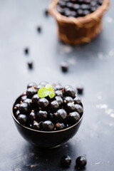 Ripe black currants in a black bowl on a table