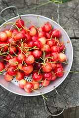 A sweet cherries in a metal sieve on a wooden stump