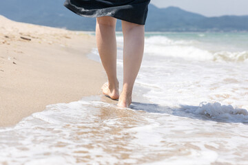 해변의 파도속을 걸어가는 여성의 다리
