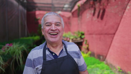 Joyful experienced senior gardner putting basket of plots of plants on shelf standing in rural backyard outside