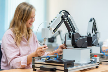 Kid female teen child enjoy Machine Learning Robot arm is Moving Under Control robot at technology class, stem education robot arms for digital automation software for artificial intelligence ai
