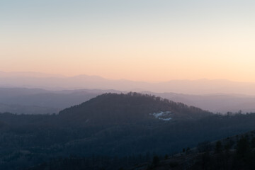 Landscape with hill overgrown in forest against mountain layers fading in distance, view from mountain Ljubic near Prnjavor