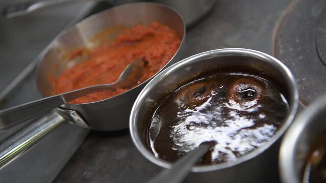 Close up shot of chef cook, sauces prepared and heated in pans on the stove, Process of making gourmet dishes, Concept of working on restaurant kitchen, High quality 4k footage