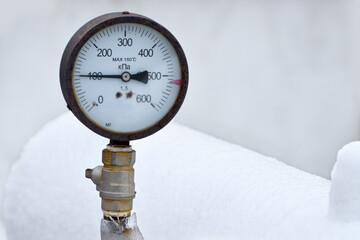 Old frozen pressure gauge on gas pipe in winter.