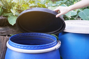 Closeup hand hold lid to cover water bucket to protect from mosquito to breed inside or other ...