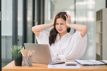 Tired frustrated young asian businesswoman feeling stressed holding head with hands, business problem failure concept.