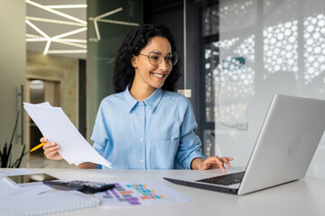 latin american businesswoman working inside office with documents and laptop, worker paperwork...