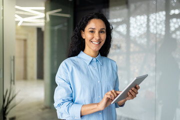 Young and successful female programmer, portrait of female engineer with tablet computer startup worker working inside office building using tablet for testing applications smiling looking at camera