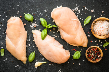 Chicken fillet, raw chicken meat breast with spices at dark background. Top view with space for...