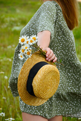 A young woman in a straw hat  on a chamomile field. Happy lady and nature - the concept of harmony. The idea of self-care, healthy lifestyle and positive