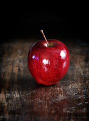 Red apple on a grunge wooden table, dark background
