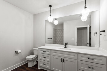 brand new white bathroom with black light fixtures, white counter tops and white, painted cabinets