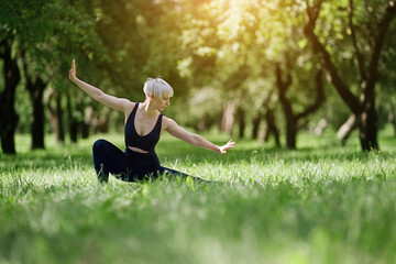 Young woman doing yoga exercise outdoor in the park, sport yoga concept	
