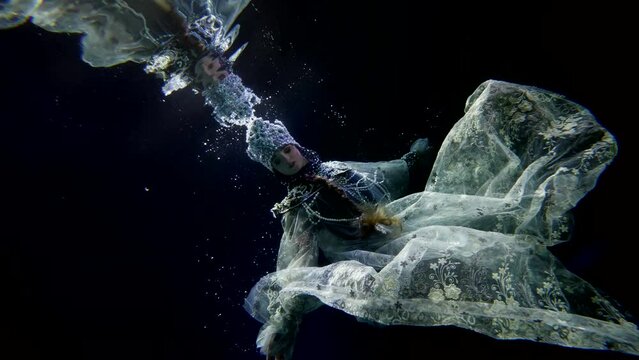 enigmatic female figure in dark depth, undersea queen floating underwater, woman in gown with pearls