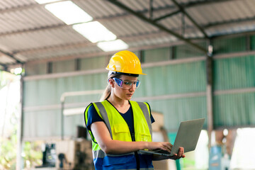 Portrait of  female industrial engineer wearing a hard hat and holding a tablet stands in a factory. Foreman in a large industrial warehouse.