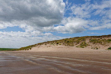 The high Dunes down the length of South Lunan Beach on the East Coast of Scotland near to Arbroath, with the tide out.