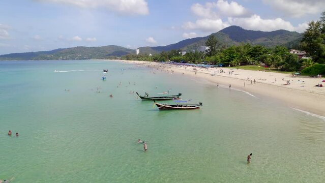 Karon beach Phuket, moored boats, speedboats, aerial photography, drone. Turquoise water and people resting, beautiful boats moored near the shore, coastline. High quality 4k footage
