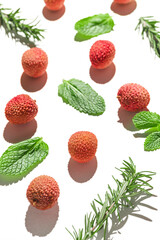 Fresh lychee fruits with rosemary and mint leaves on white background. Minimal style composition. Healthy food concept. Summer refreshment theme