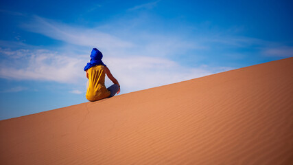 Woman sitting on sand dune in Sahara desert- travel, adventure, wanderlust concept © M.studio